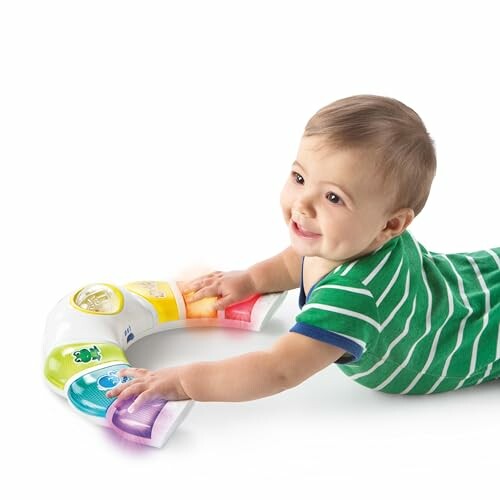 Baby in green striped shirt playing with a colorful toy.