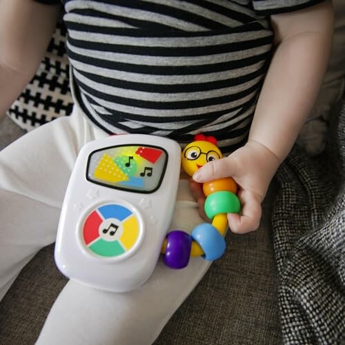 Baby holding a colorful musical toy.