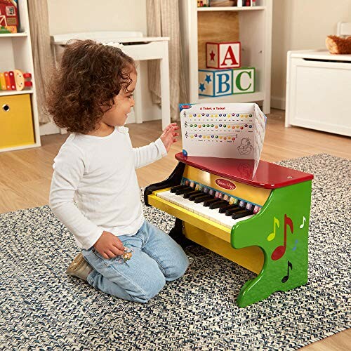 Child playing a colorful toy piano with music book.