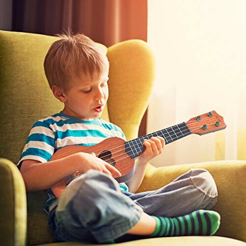 Child sitting on chair playing ukulele.