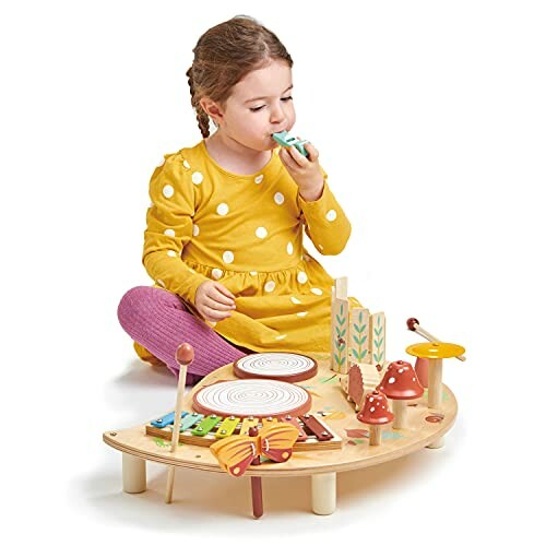 Child in yellow dress playing with a wooden musical toy.
