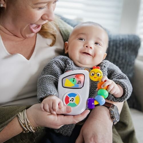 Baby holding colorful toy with smiling adult.