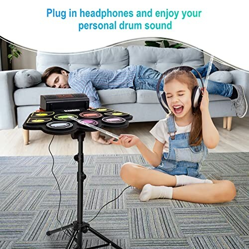 Child enjoying headphones with electronic drum set, adult resting on sofa.