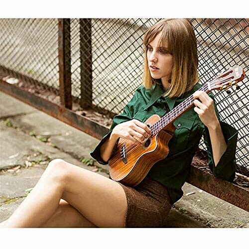Woman sitting and playing a ukulele outdoors.